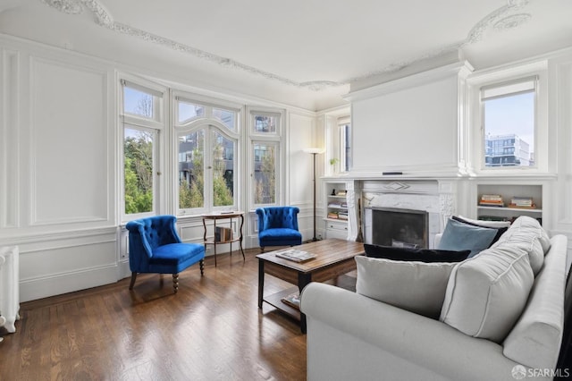 living room with a high end fireplace, radiator heating unit, dark hardwood / wood-style flooring, and ornamental molding