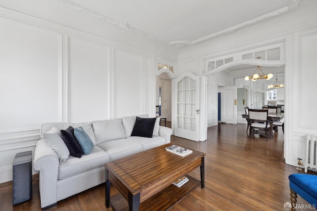 living room featuring dark hardwood / wood-style floors, crown molding, radiator, and a notable chandelier