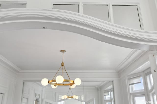 details featuring ornamental molding and an inviting chandelier