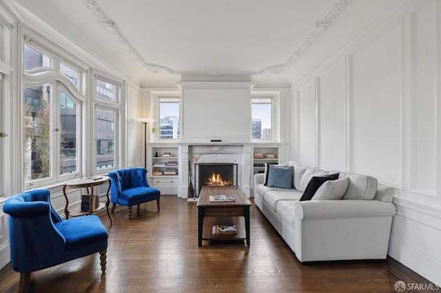 living room with a high end fireplace, dark wood-type flooring, a wealth of natural light, and ornamental molding