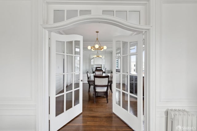 dining area with french doors, radiator heating unit, dark hardwood / wood-style floors, a notable chandelier, and crown molding