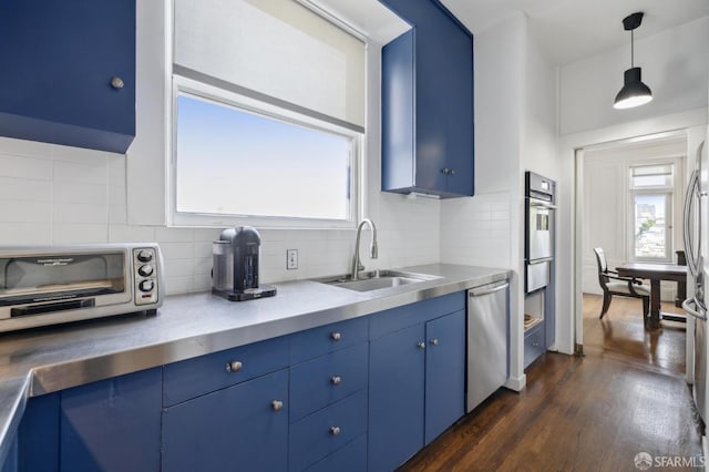 kitchen with blue cabinetry, sink, stainless steel appliances, dark hardwood / wood-style floors, and pendant lighting