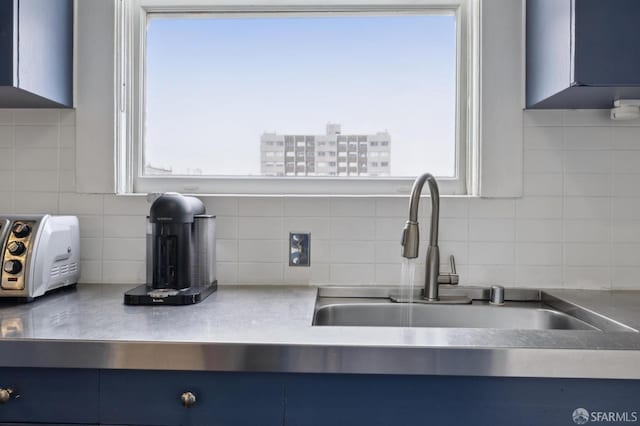 room details featuring tasteful backsplash, blue cabinets, and sink