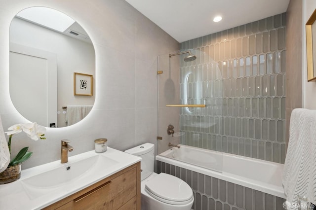 full bathroom with vanity, tile walls, toilet, and tiled shower / bath