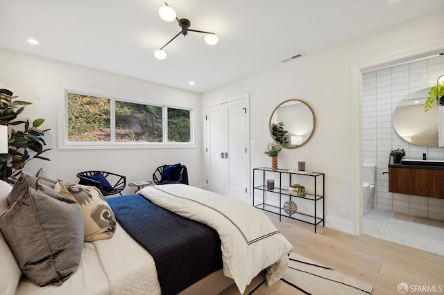 bedroom featuring ensuite bath, light hardwood / wood-style floors, and a closet