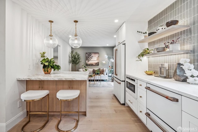 kitchen with high end fridge, light stone counters, tasteful backsplash, and white cabinets