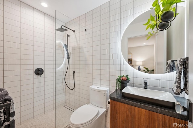 bathroom with tile walls, tiled shower, vanity, decorative backsplash, and toilet