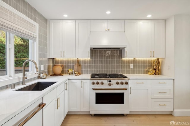 kitchen featuring white cabinetry, white range oven, sink, and custom range hood