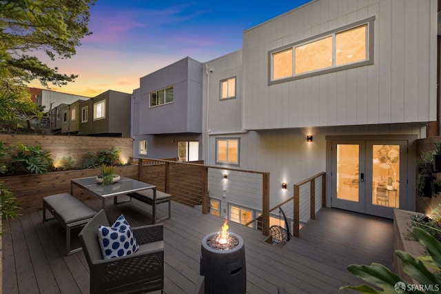 deck at dusk with french doors and a fire pit