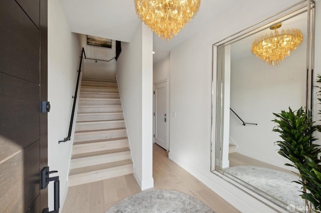 staircase featuring hardwood / wood-style floors and a notable chandelier