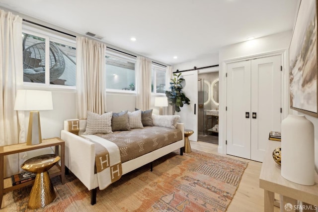 sitting room with light hardwood / wood-style flooring, a wealth of natural light, and a barn door