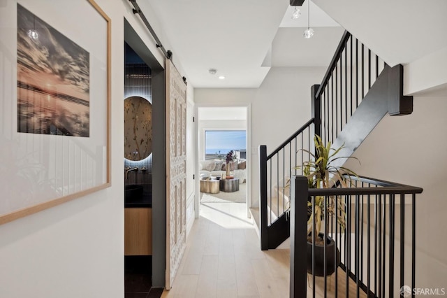 hallway with a barn door and hardwood / wood-style floors