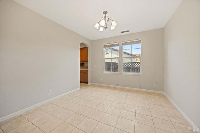 tiled empty room featuring a chandelier