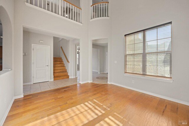 unfurnished living room featuring a towering ceiling and light hardwood / wood-style floors