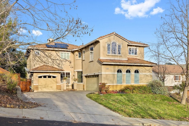 mediterranean / spanish-style house featuring solar panels, a garage, and a front yard