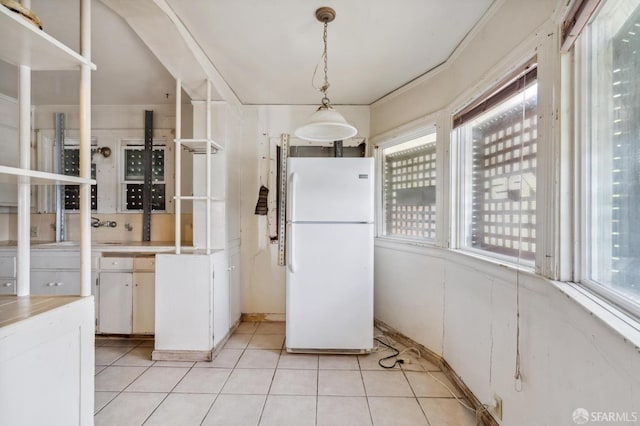 4770 Tompkins Ave, Oakland, CA 94619 - kitchen featuring freestanding refrigerator, light tile patterned flooring, hanging light fixtures, light countertops, and white cabinetry