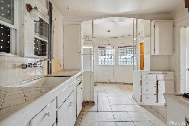 4770 Tompkins Ave, Oakland, CA 94619 - kitchen featuring backsplash, white cabinetry, a sink, and light tile patterned flooring