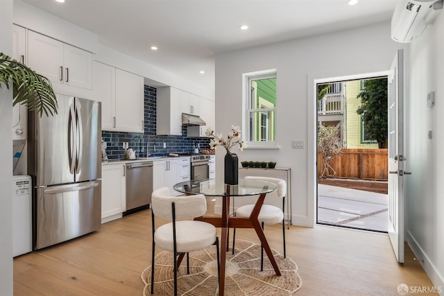 152-154 Ord St, San Francisco, CA 94114 - kitchen featuring appliances with stainless steel finishes, a wall mounted air conditioner, under cabinet range hood, light wood finished floors, and recessed lighting
