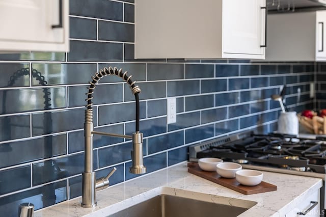 152-154 Ord St, San Francisco, CA 94114 - kitchen view of tasteful backsplash, light stone counters, white cabinets, a sink, and ventilation hood