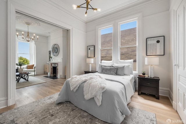 152-154 Ord St, San Francisco, CA 94114 - bedroom featuring a chandelier, crown molding, light wood-style flooring, a fireplace with flush hearth, and baseboards