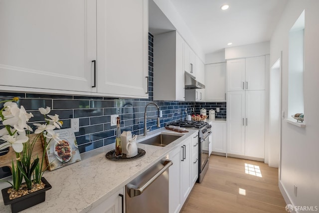 152-154 Ord St, San Francisco, CA 94114 - kitchen featuring stainless steel appliances, a sink, under cabinet range hood, light wood-style flooring, and white cabinets