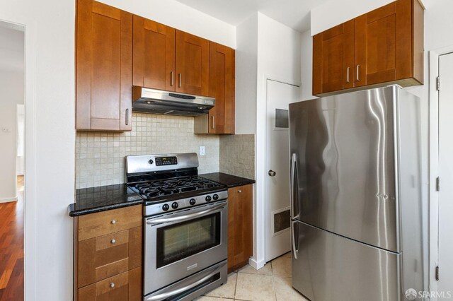 906 40th St, Oakland, CA 94608 - kitchen with under cabinet range hood, appliances with stainless steel finishes, tasteful backsplash, and dark stone countertops