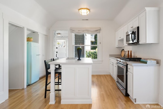 kitchen featuring white cabinets, a kitchen bar, stainless steel appliances, and light countertops