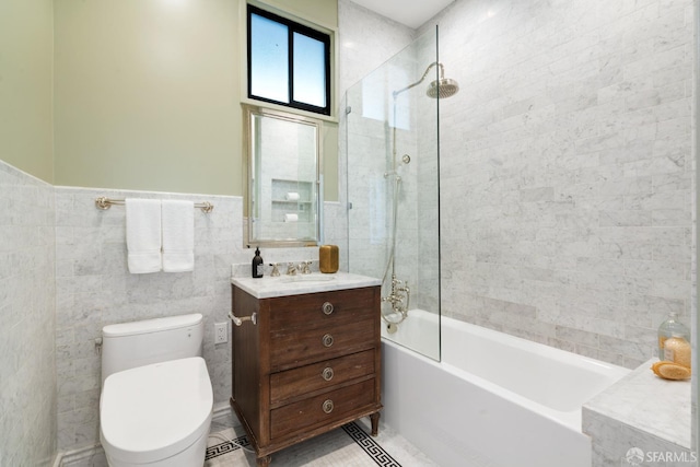 bathroom with a wainscoted wall, tile walls, toilet, vanity, and shower / tub combination