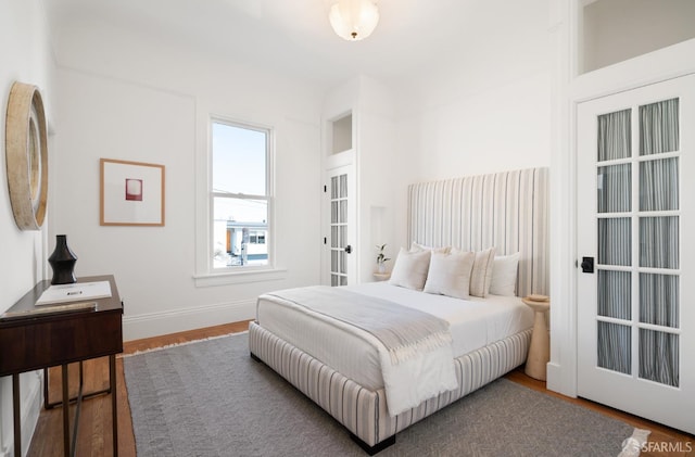 bedroom featuring french doors, wood finished floors, and baseboards