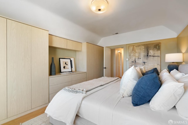 bedroom featuring visible vents, vaulted ceiling, and light wood-style flooring