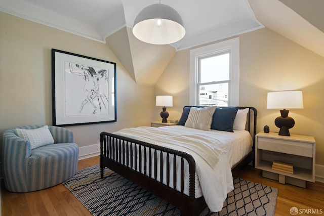 bedroom featuring lofted ceiling, baseboards, and wood finished floors