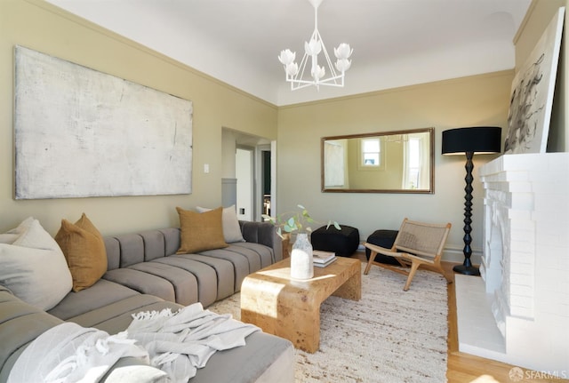 living area featuring ornamental molding, a fireplace, a notable chandelier, and wood finished floors