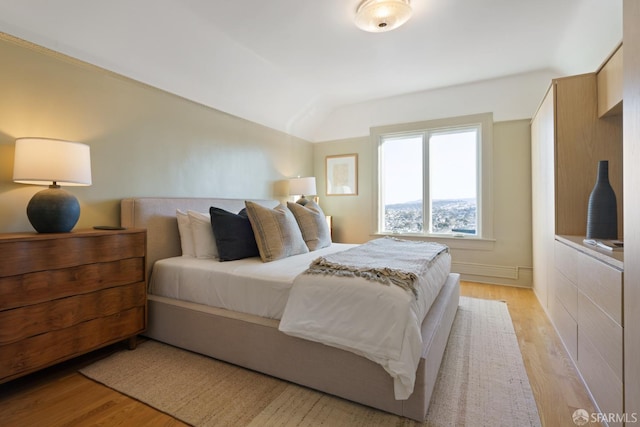 bedroom featuring lofted ceiling and light wood finished floors