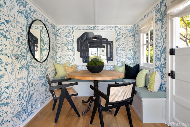 dining space with breakfast area, wood finished floors, and wallpapered walls