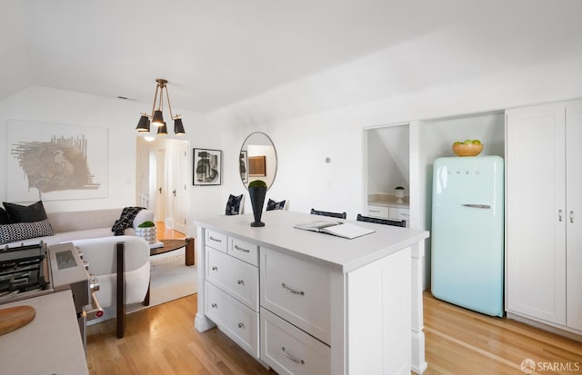 kitchen with light countertops, light wood finished floors, freestanding refrigerator, and white cabinetry