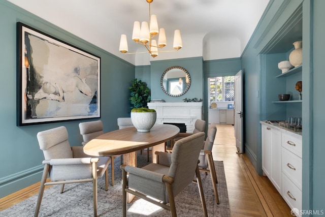 dining space featuring a chandelier, a fireplace, wood finished floors, and baseboards