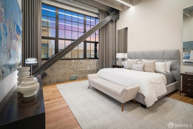 bedroom featuring wood-type flooring and a towering ceiling