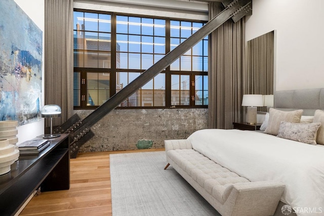 bedroom featuring wood-type flooring and a high ceiling