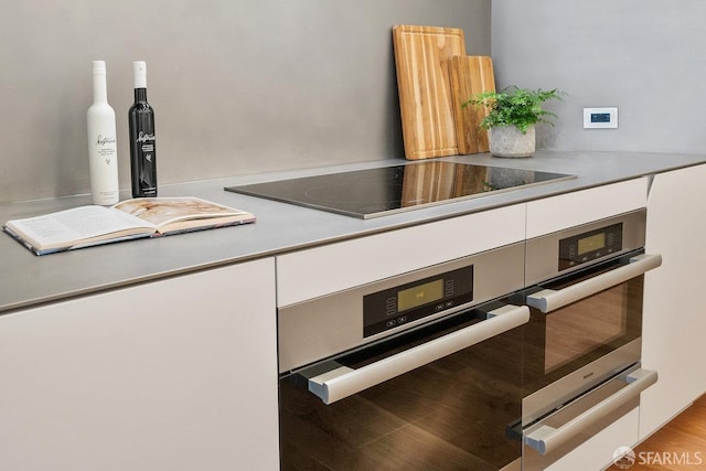 interior details featuring double oven, black electric stovetop, and white cabinets