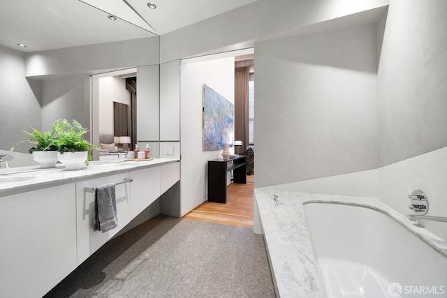 bathroom with a tub, hardwood / wood-style floors, and vanity