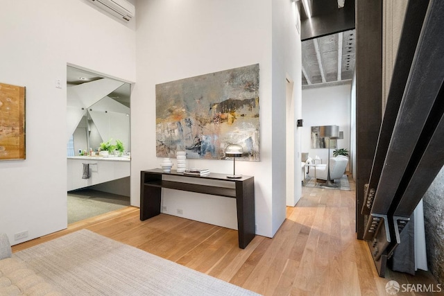 hall featuring a wall mounted AC, a towering ceiling, and wood-type flooring