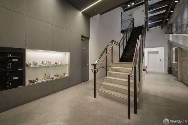 staircase with a towering ceiling and concrete floors