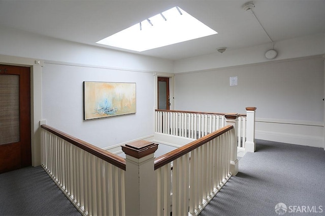 corridor with a skylight and dark colored carpet