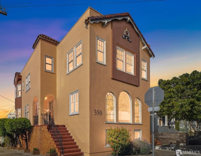view of front of house featuring stucco siding and stairway