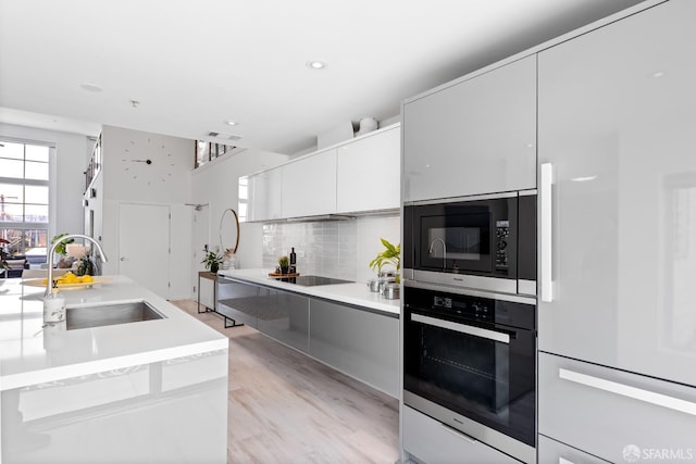 229 8th St Unit 3, San Francisco, CA 94103 - kitchen with black appliances, modern cabinets, decorative backsplash, white cabinetry, and light countertops