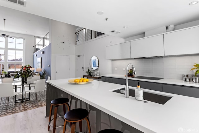 229 8th St Unit 3, San Francisco, CA 94103 - kitchen with a breakfast bar, light countertops, tasteful backsplash, light wood finished floors, and a towering ceiling
