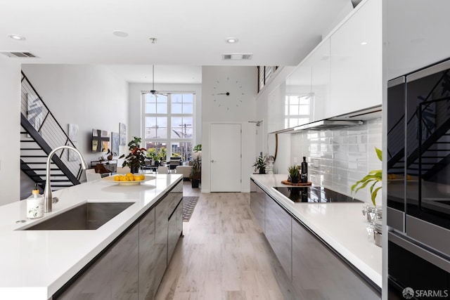 229 8th St Unit 3, San Francisco, CA 94103 - kitchen with modern cabinets, black electric stovetop, a ceiling fan, light wood finished floors, and light countertops