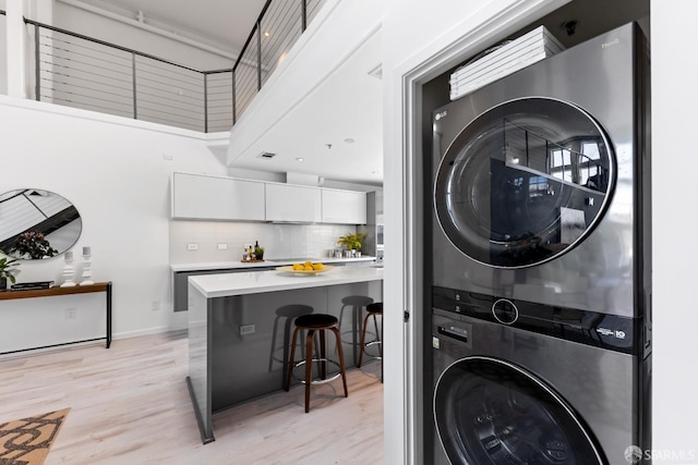 229 8th St Unit 3, San Francisco, CA 94103 - laundry area with stacked washing machine and dryer, light wood-type flooring, and a high ceiling