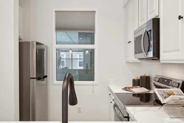 kitchen with white cabinetry, appliances with stainless steel finishes, and light stone countertops