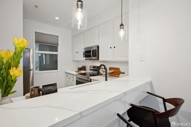 kitchen featuring pendant lighting, white cabinetry, stainless steel appliances, light stone counters, and kitchen peninsula